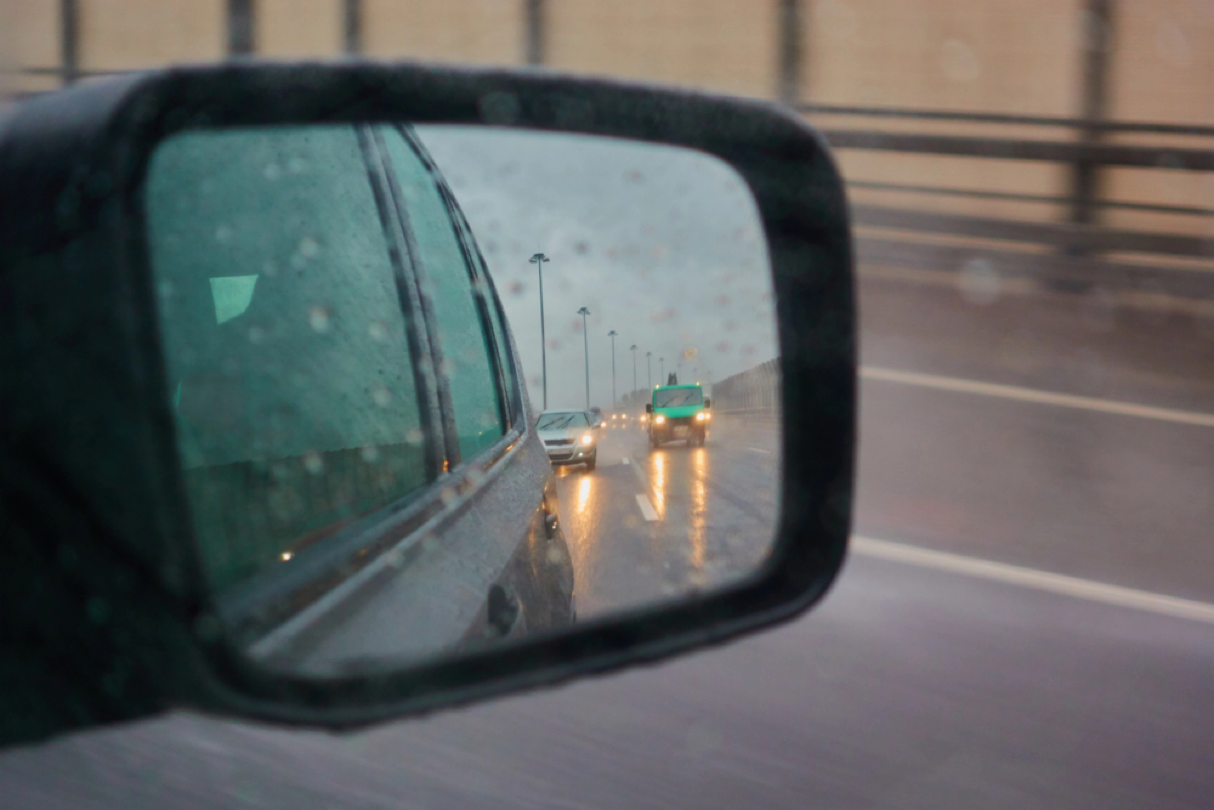 The reflection from a car's side-mirror, showing the road behind.